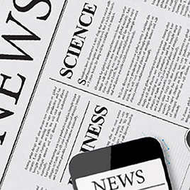 A newspaper features sections titled "Science" and "Business," with articles in each. Demonstrating the essence of journalism, a smartphone displaying a headline is partially visible at the bottom edge of the image.