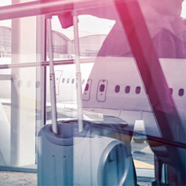 A suitcase with extended handles is positioned by a large window with an airplane visible outside at an airport terminal, ready for a quick response in any corporate crisis management situation.