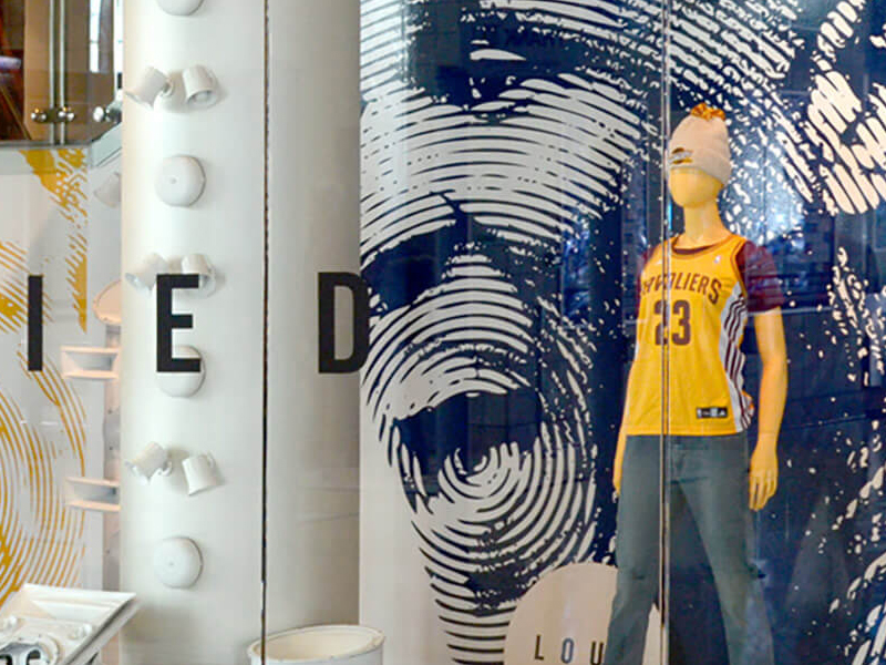 A retail display features a mannequin dressed in a Cleveland Cavaliers basketball jersey and jeans, with a large fingerprint design and the word "DIED" partially visible on the background wall.