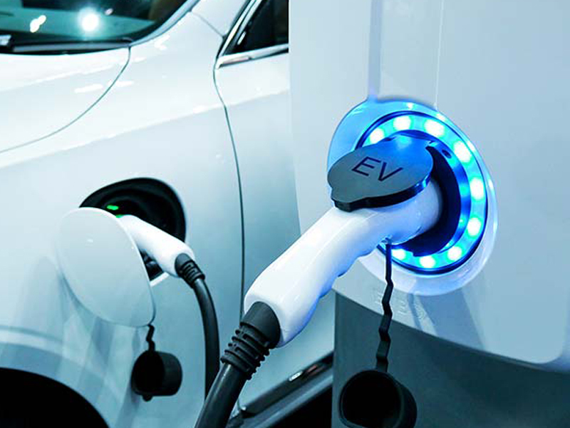 An electric vehicle is plugged into a charging station with a blue light indicator illuminating the connection point, showcasing cutting-edge Neograf technology.