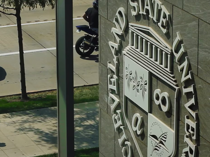 A motorcycle is parked on a street near a building, proudly displaying the CSU emblem.