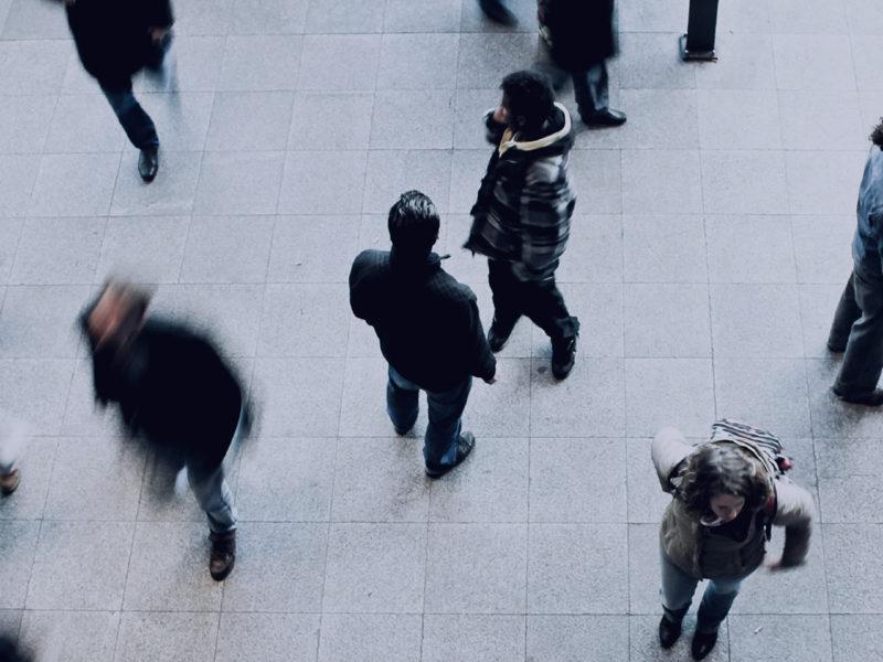 Overhead view of several people, including some from McDonald Hopkins, walking and standing on a tiled floor, captured with some motion blur.