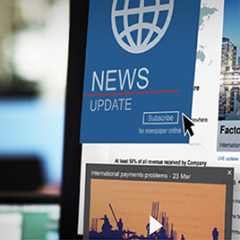 A close-up of a computer screen displaying a news update, a "Subscribe" button, and an article titled "International payments problems - 23 Mar" beside other digital business coverage.