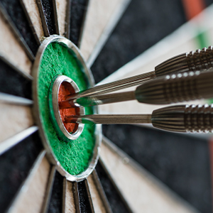 Three darts expertly hit the bullseye on a dartboard, showcasing what it means to do them well.