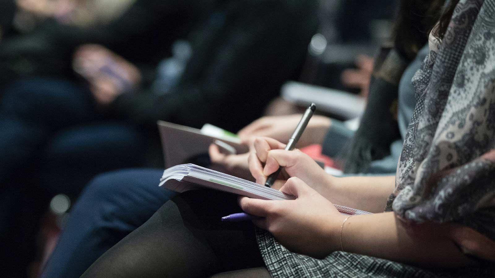 Former journalists and content mavens seated closely, attentively taking notes in notebooks during Content Marketing World.