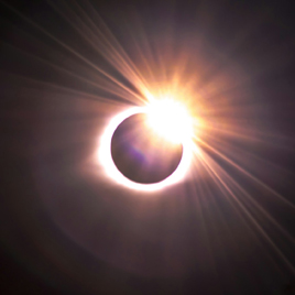 An image of a total eclipse in April 2024, capturing the sun's corona and the bright light peeking from behind the moon as it follows the path of totality.