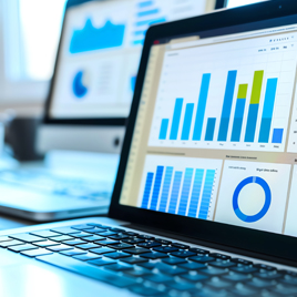 A close-up of a laptop displaying charts and graphs on how to measure earned media, with another screen showing similar data in the background.